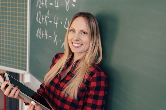 Woman holding tablet in front of chalk board