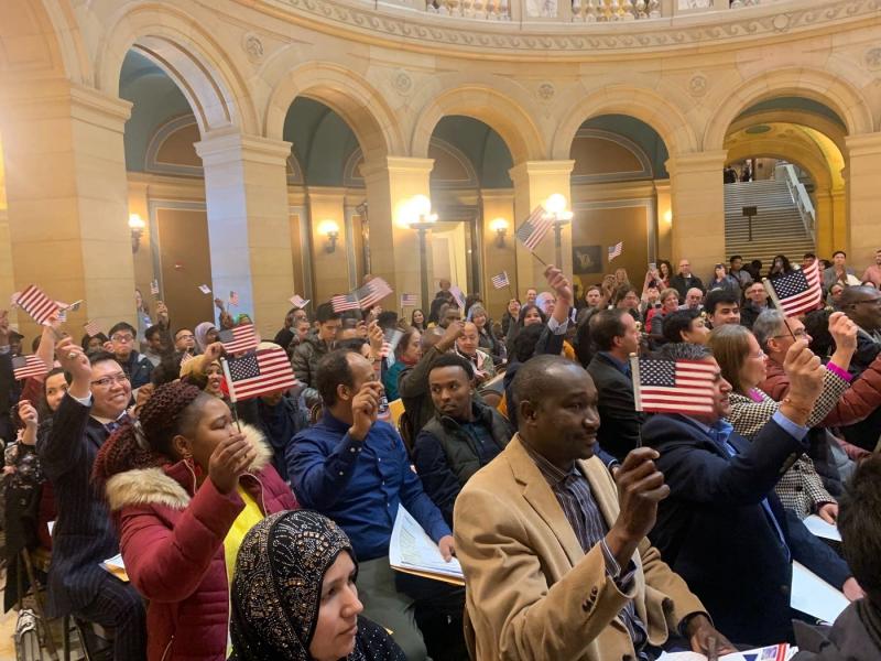 New citizens wave flags after taking the oath of citizenship at the state Capitol in St. Paul